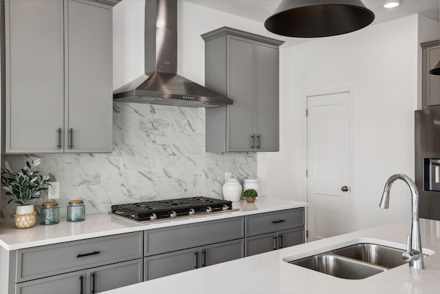 kitchen featuring backsplash, sink, wall chimney exhaust hood, gray cabinets, and appliances with stainless steel finishes