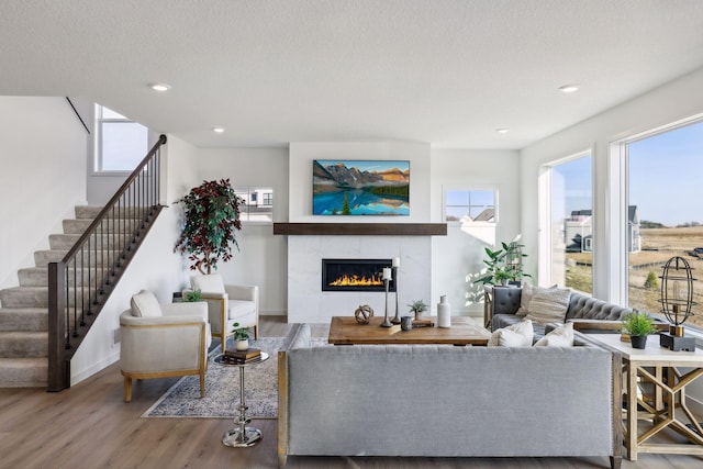 living room with hardwood / wood-style flooring, plenty of natural light, a textured ceiling, and a tiled fireplace