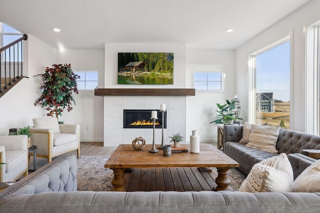 living room featuring a tile fireplace, plenty of natural light, and hardwood / wood-style flooring