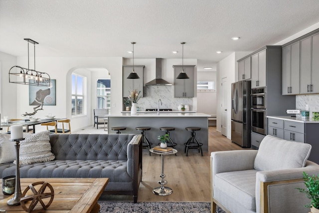 living room featuring a textured ceiling, sink, a notable chandelier, and light wood-type flooring