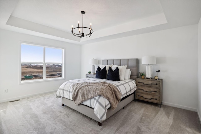 carpeted bedroom featuring a chandelier and a tray ceiling