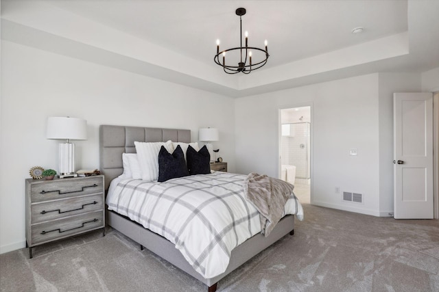 carpeted bedroom featuring a raised ceiling, ensuite bathroom, and a notable chandelier