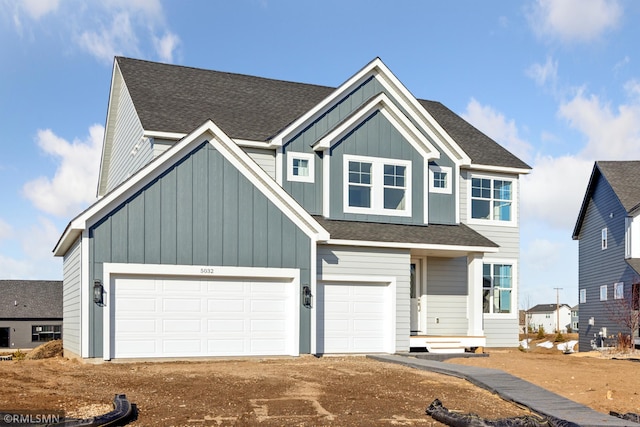 view of front facade with dirt driveway, a garage, board and batten siding, and roof with shingles