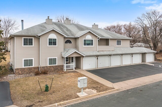 view of front of home featuring aphalt driveway, a chimney, a garage, and brick siding