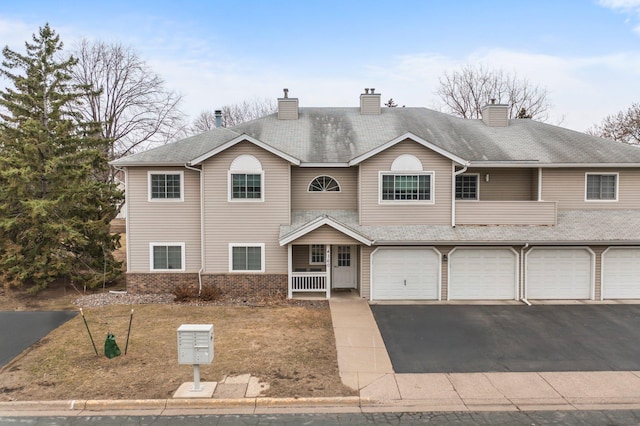 view of front of house featuring a garage, brick siding, a chimney, and driveway