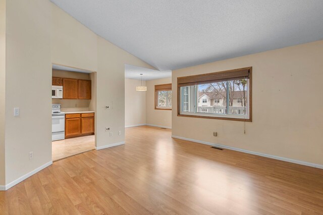 unfurnished living room with baseboards, light wood-type flooring, lofted ceiling, and visible vents