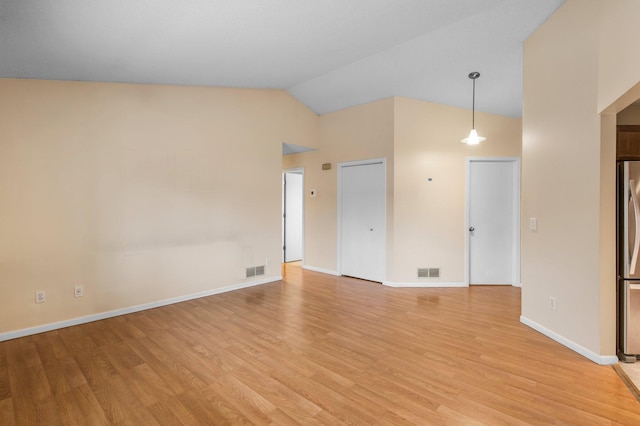 empty room featuring lofted ceiling, visible vents, and light wood finished floors