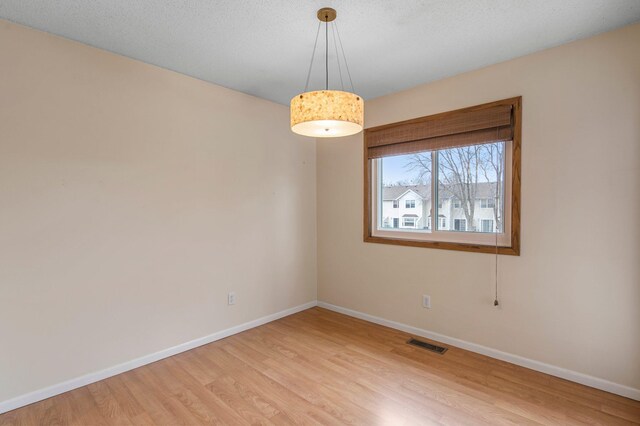 empty room with visible vents, baseboards, and light wood finished floors
