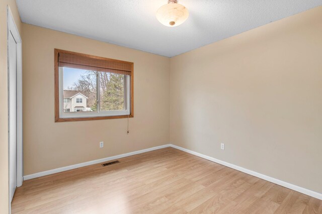 spare room featuring light wood-style flooring, visible vents, and baseboards