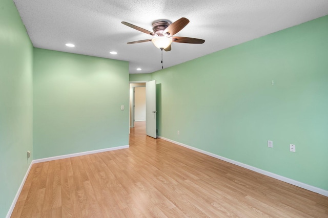 spare room with a ceiling fan, baseboards, recessed lighting, light wood-style floors, and a textured ceiling