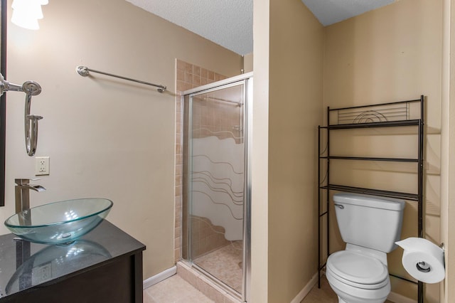 bathroom with tile patterned floors, toilet, a textured ceiling, a shower stall, and baseboards