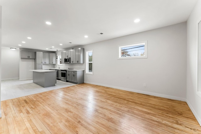 kitchen featuring gray cabinets, a kitchen island, stainless steel appliances, and light hardwood / wood-style flooring