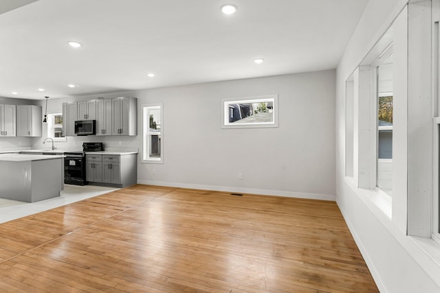 unfurnished living room featuring a wealth of natural light, sink, and light hardwood / wood-style floors