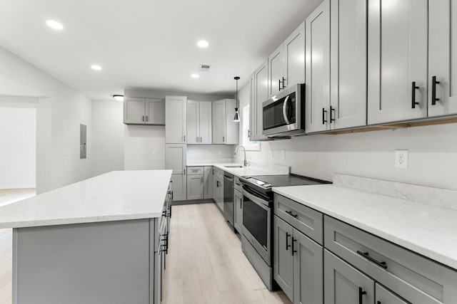 kitchen featuring light wood-type flooring, gray cabinetry, stainless steel appliances, sink, and pendant lighting