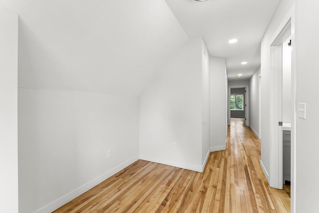 hallway with light wood-type flooring and lofted ceiling