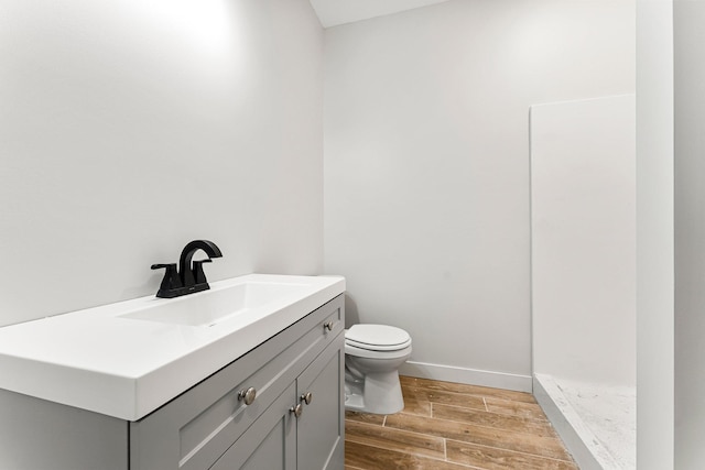 bathroom featuring hardwood / wood-style floors, vanity, toilet, and a shower