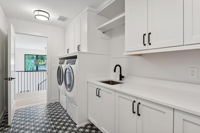 clothes washing area with cabinets, washer and clothes dryer, and sink