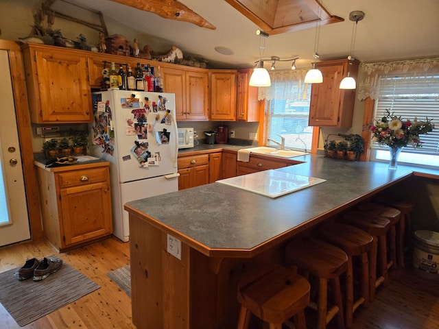 kitchen with sink, hanging light fixtures, kitchen peninsula, white appliances, and light wood-type flooring