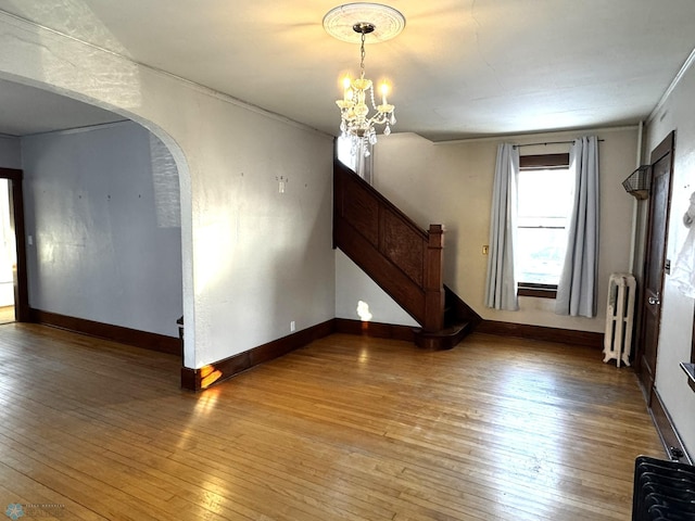 empty room featuring radiator, a notable chandelier, and hardwood / wood-style flooring