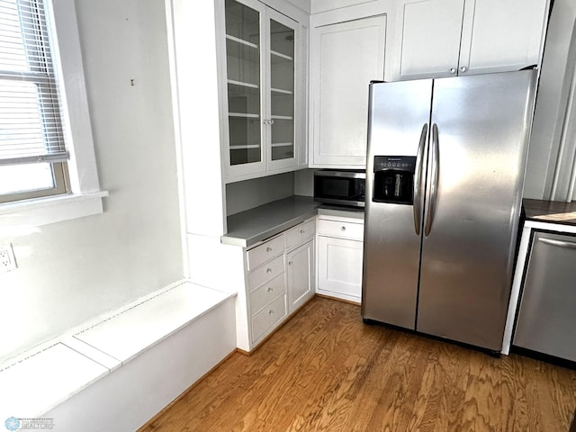 kitchen featuring white cabinets, appliances with stainless steel finishes, and hardwood / wood-style flooring