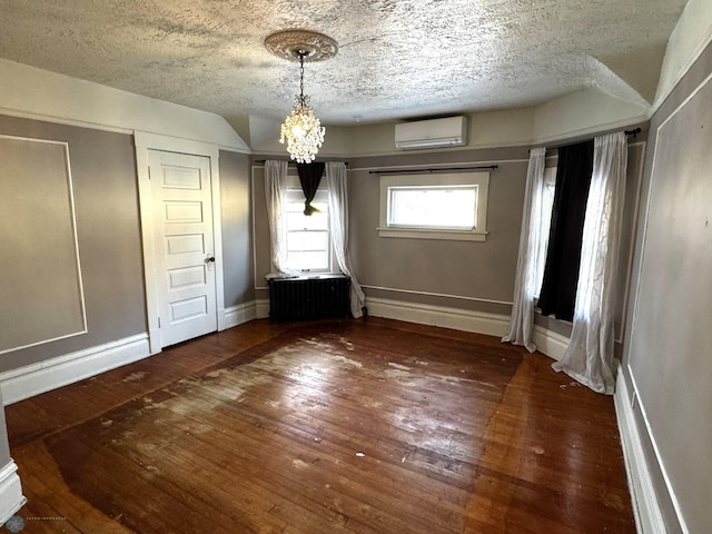 interior space featuring radiator, dark wood-type flooring, a wall unit AC, a chandelier, and a textured ceiling