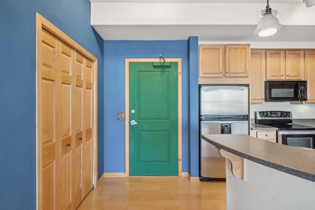 kitchen with light hardwood / wood-style flooring, hanging light fixtures, light brown cabinets, and appliances with stainless steel finishes