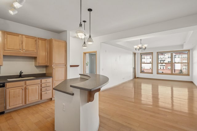 kitchen with pendant lighting, dishwasher, sink, light hardwood / wood-style floors, and a chandelier