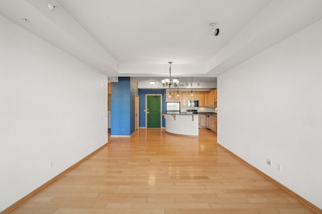 interior space with stainless steel refrigerator, an inviting chandelier, light hardwood / wood-style flooring, decorative light fixtures, and a breakfast bar