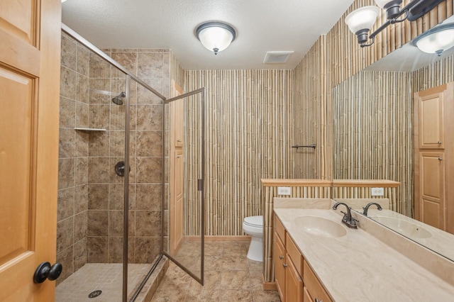 bathroom featuring vanity, tile patterned flooring, toilet, a textured ceiling, and a shower with shower door