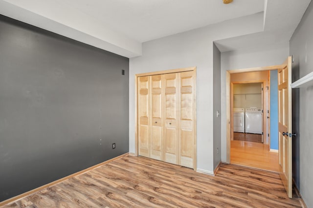 unfurnished bedroom featuring washing machine and dryer, a closet, and wood-type flooring