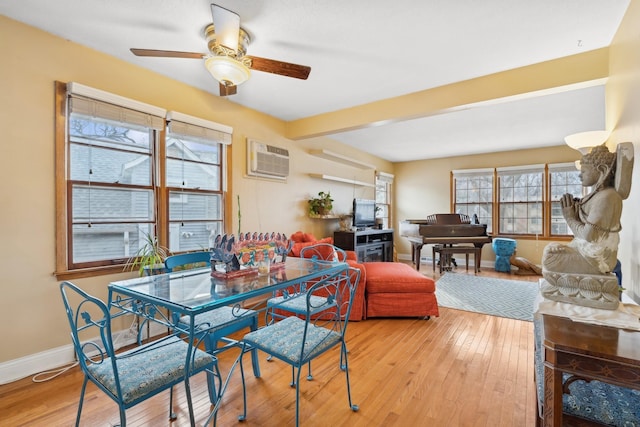 dining area with ceiling fan, a healthy amount of sunlight, a wall mounted air conditioner, and light wood-type flooring