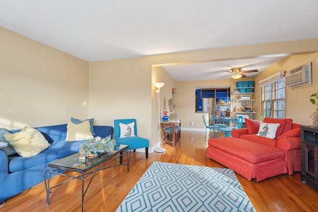 living room featuring hardwood / wood-style floors, ceiling fan, beam ceiling, and an AC wall unit