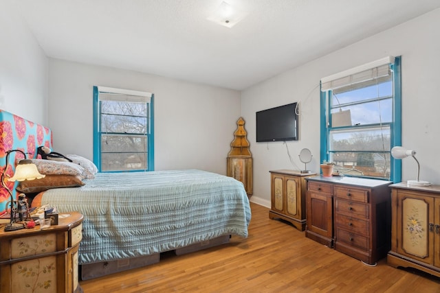 bedroom with multiple windows and light hardwood / wood-style flooring