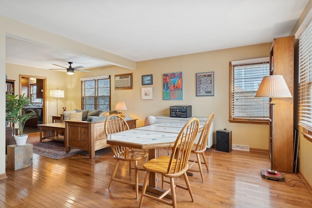 dining room featuring a wall mounted AC, light wood-type flooring, ceiling fan, and beamed ceiling