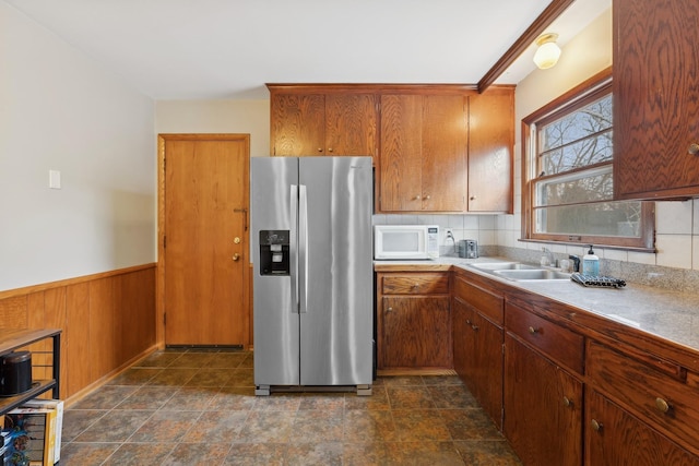 kitchen with stainless steel fridge, wooden walls, and sink