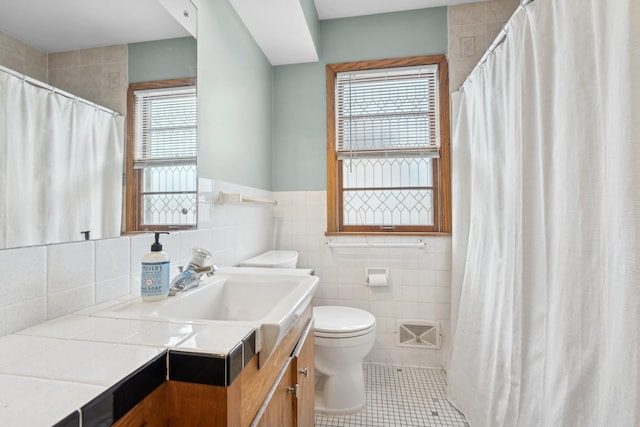 bathroom featuring curtained shower, tile patterned flooring, toilet, vanity, and tile walls