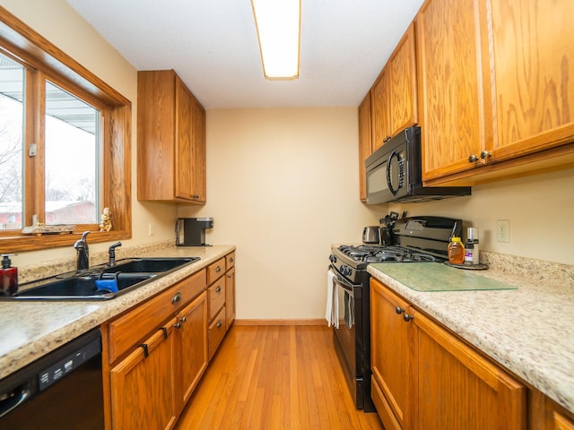 kitchen featuring sink, light hardwood / wood-style floors, and black appliances