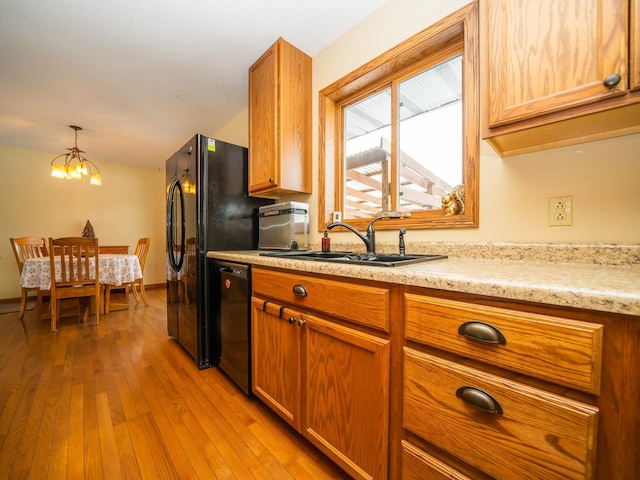 kitchen with dishwasher, decorative light fixtures, sink, a chandelier, and light wood-type flooring