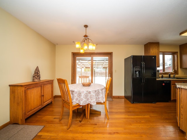 dining area with sink, light hardwood / wood-style flooring, and a notable chandelier