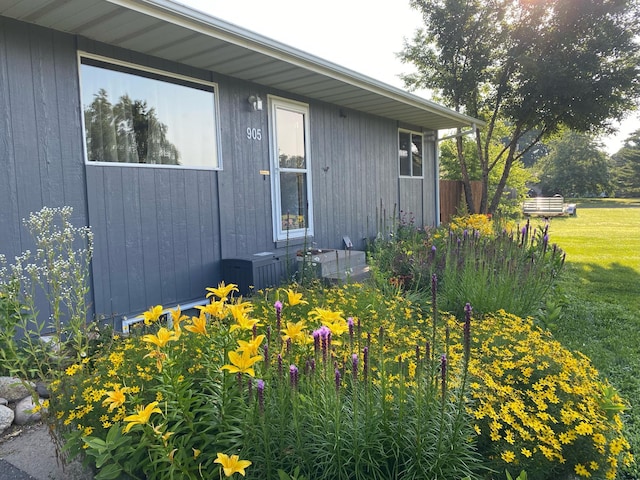 view of exterior entry featuring a lawn and central air condition unit