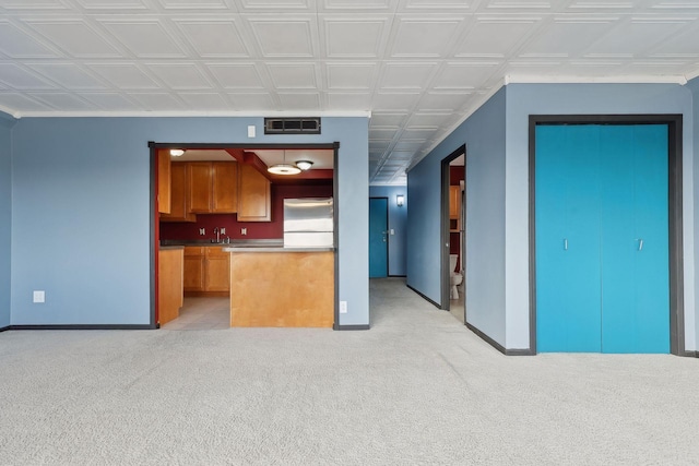 kitchen featuring light colored carpet, stainless steel fridge, and sink