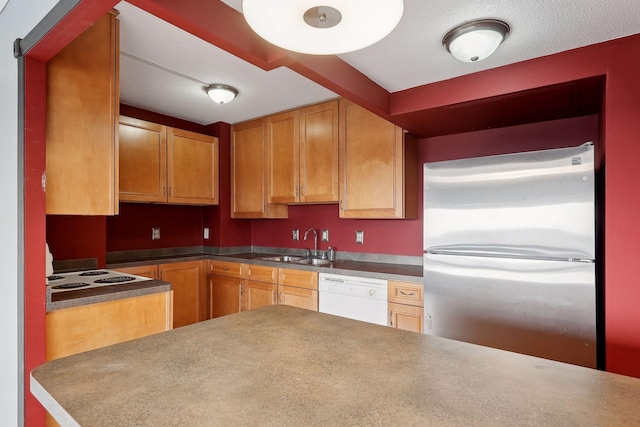 kitchen featuring white dishwasher, sink, and stainless steel fridge