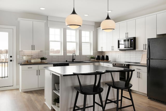 kitchen featuring white cabinetry, hanging light fixtures, and appliances with stainless steel finishes