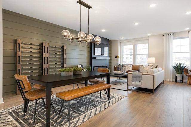 dining room featuring wood-type flooring, a notable chandelier, and wood walls