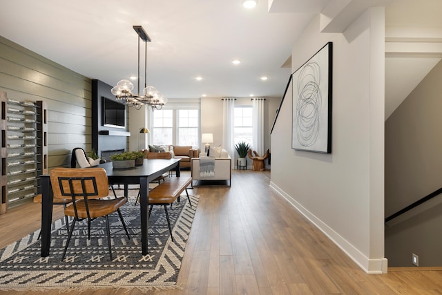 dining room with wood-type flooring, a fireplace, and an inviting chandelier