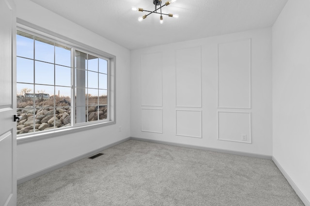 empty room featuring a chandelier and light carpet