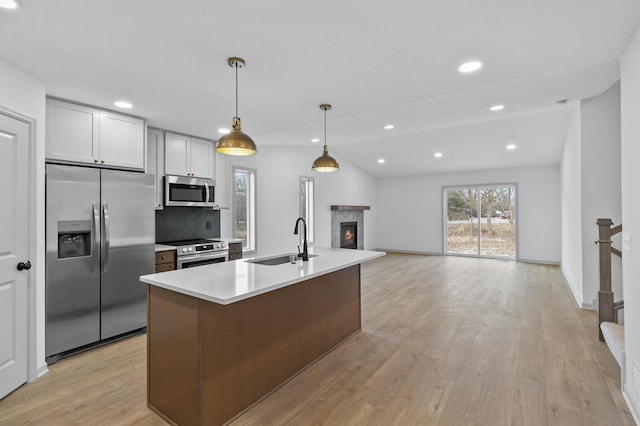 kitchen featuring white cabinetry, sink, hanging light fixtures, stainless steel appliances, and a kitchen island