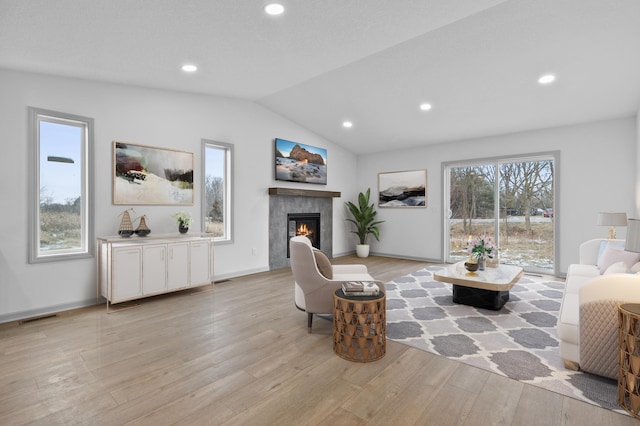 living room featuring a fireplace, light hardwood / wood-style flooring, and vaulted ceiling