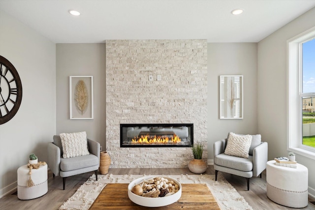 sitting room with light hardwood / wood-style floors and a stone fireplace