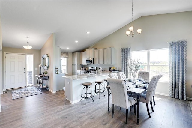 dining space featuring high vaulted ceiling, a notable chandelier, and light wood-type flooring